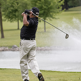 Golfer swinging in front of a fountain