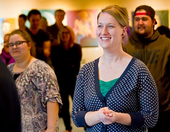 A Lakeland University students smiles at an art show.