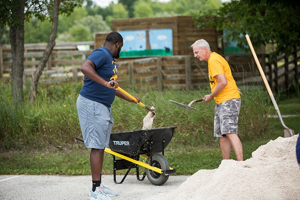A Lakeland student and a volunteer fill up a wheel barrel