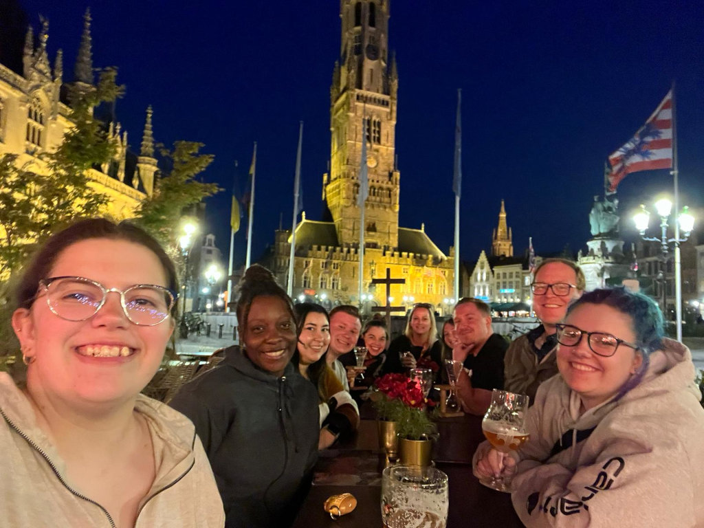 Group photo of students outside at night, an European church is visible in the background