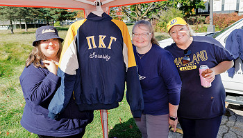2025 homecoming photo - group under a tailgating tent with a Greek organization jacket